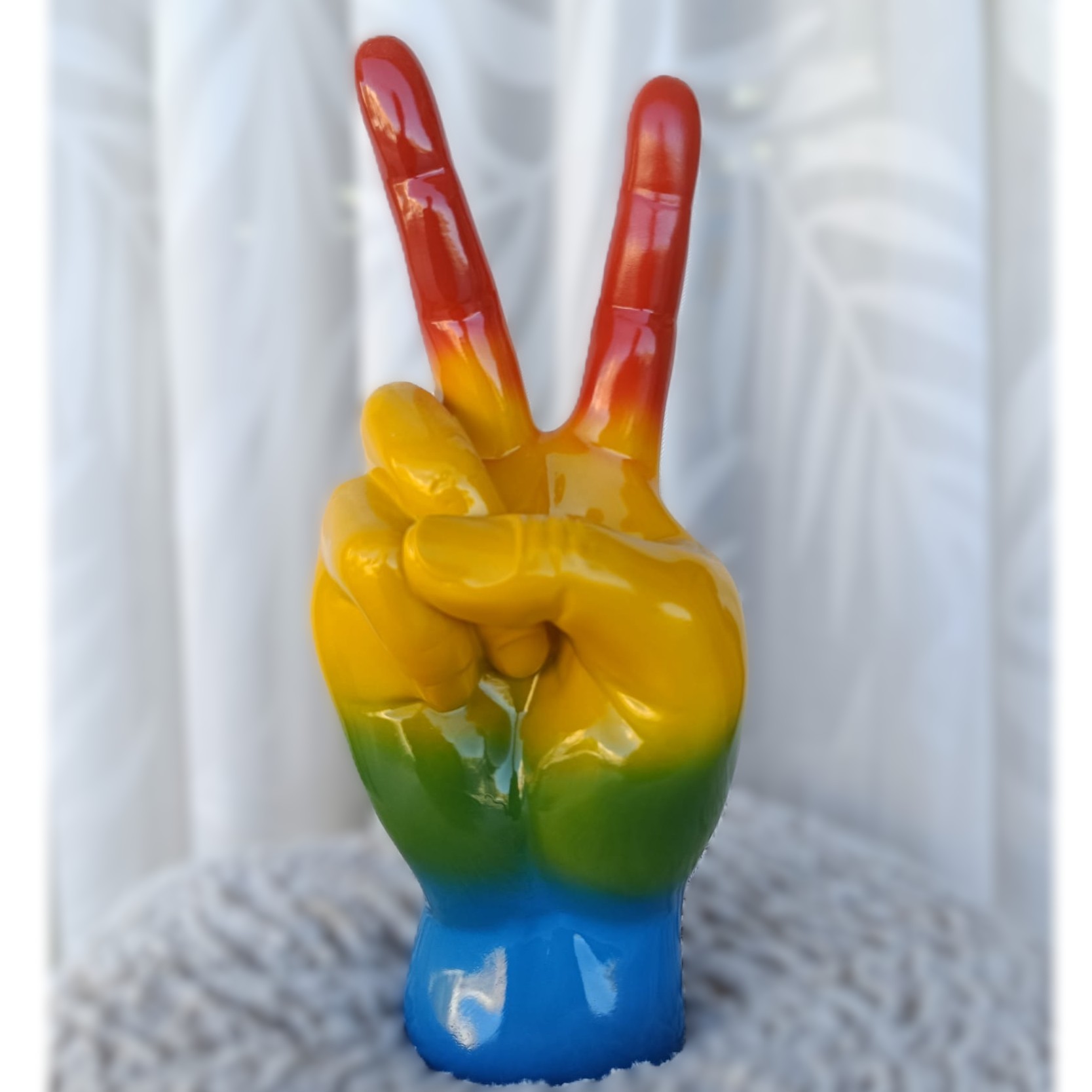 Figura de resina con forma de mano con motivo arcoíris.